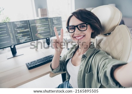 Portrait of cheerful charming hardware expert make selfie fingers show v-sign sitting chair office indoors