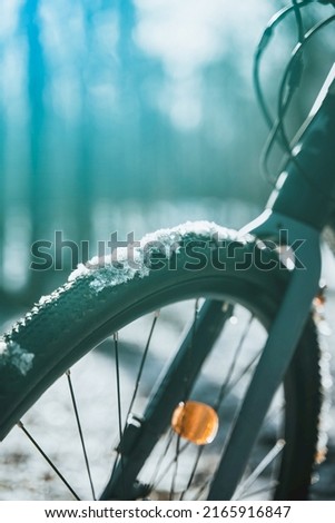Close up of a front cycle wheel covered with snow. Concept of cycling during snowy weather. Bike riding at bad weather