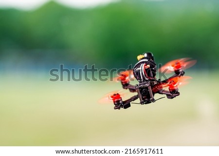 Freestyle FPV quadcopter drone background with blurred hills.