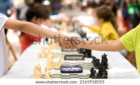 Children's handshake after finishing the game of chess as a sign of sportsmanship and fair play.  children fairness, justice, equality, fidelity, honesty.Concept of kids doing sports. world chess day Royalty-Free Stock Photo #2165918593