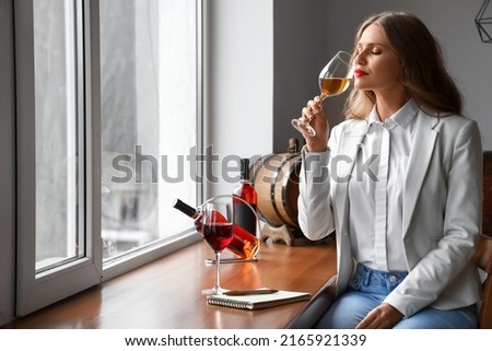 Beautiful young female sommelier tasting types of wine Royalty-Free Stock Photo #2165921339