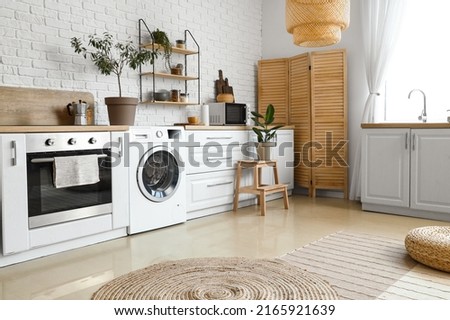 Stylish interior of kitchen with modern washing machine Royalty-Free Stock Photo #2165921639