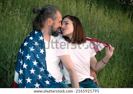 Loving couple celebrating USA Independence Day. Couple in love kissing and holding USA flag. July 4th
