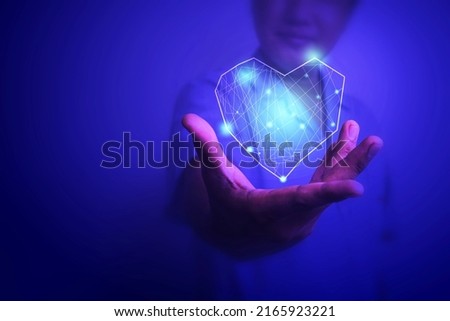 Doctor hand holding digital heart icon with blur background blue tone, health care concept.