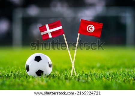 October 2022: Denmark vs. Tunisia, Education City,, Football match wallpaper, Handmade national flags and soccer ball on green grass. Football stadium in background. Black edit space. Royalty-Free Stock Photo #2165924721