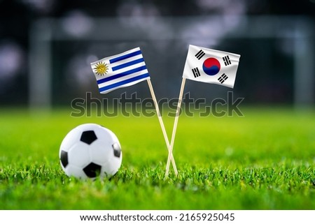 October 2022: Uruguay vs. South Korea, Education City, Football match wallpaper, Handmade national flags and soccer ball on green grass. Football stadium in background. Black edit space. Royalty-Free Stock Photo #2165925045