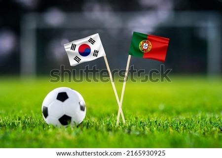 October 2022: South Korea vs. Portugal, Education City, Football match wallpaper, Handmade national flags and soccer ball on green grass. Football stadium in background. Black edit space.