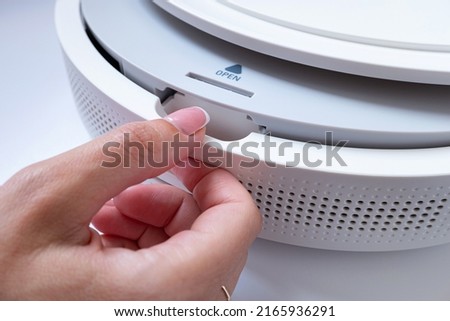Female hand opens the compartment of household appliances with the inscription Open.