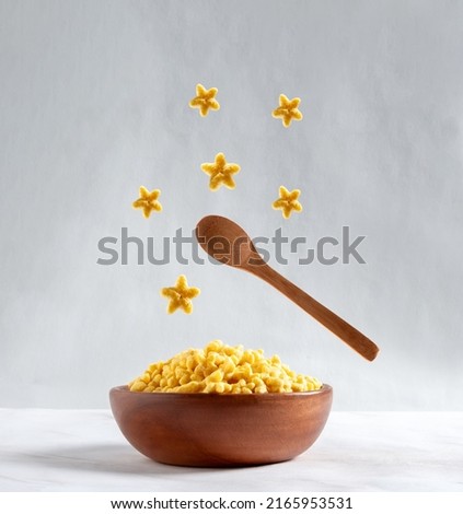 Wooden bowl with star corn flakes on gray background. Food levitation. Good morning card. 
