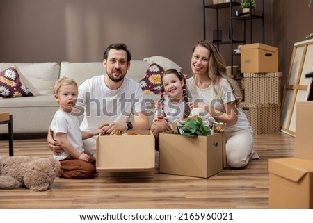 Portrait of a young family with children moving into a new home. Cooperation in unpacking boxes.