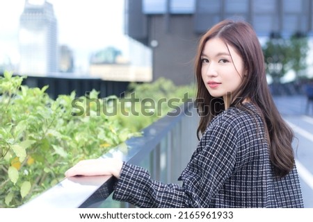 Professional confident working Asian woman who has a long hair wears a black suit black with striped shirt while walking outside the city.