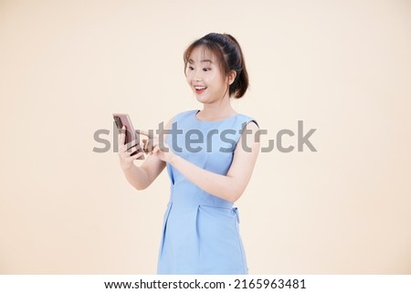 Portrait of Asian young beautiful and cheerful woman, using smart phone, isolated on background