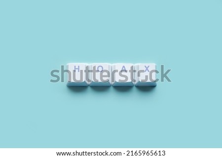 Word "HOAX" written on computer keyboard keys isolated on a blue background. Royalty-Free Stock Photo #2165965613