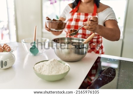 Hispanic brunette woman preparing chocolate cake at the kitchen Royalty-Free Stock Photo #2165976105