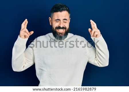 Young hispanic man wearing casual clothes gesturing finger crossed smiling with hope and eyes closed. luck and superstitious concept. 
