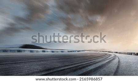 Empty long mountain road to the horizon on a sunny summer day at a bright sunset - speed motion blur effect. Royalty-Free Stock Photo #2165986857