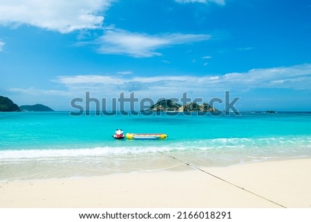 Turquoise water, clear sky, white sandy beach, and the tropical Caspian Sea with a jet ski and banana boat