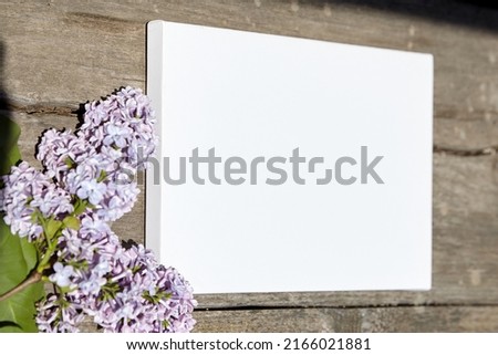 White canvas mockup with lilac flower on wooden background