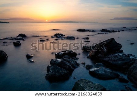 Long exposure photo of sea, rocks and sunset. Concept of relax, calm, tranquil and inner peace.
