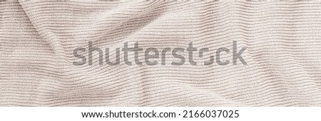 Fine knit draped cloth texture. Fashion background. Beige knitted fabric backdrop. Jersey scarf knit backdrop. Warm winter sweater. Banner. 
