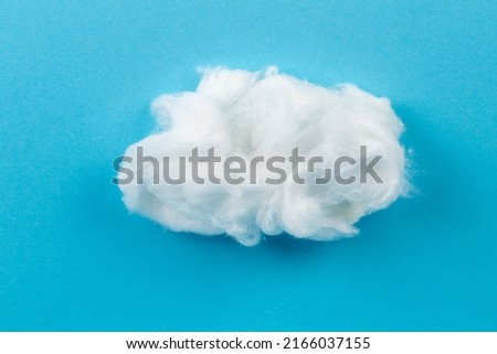 White piece of cotton wool on a blue background. Delicate cloud. Royalty-Free Stock Photo #2166037155