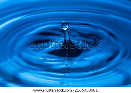 The water droplets fall on the water surface until the water spread out, creating beautiful ripples on the light blue water.