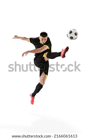 Professional male football soccer player in motion and action isolated on white studio background. Concept of sport, goals, competition, hobby, ad, world cup. Sportsmen wearing black football kit Royalty-Free Stock Photo #2166061613