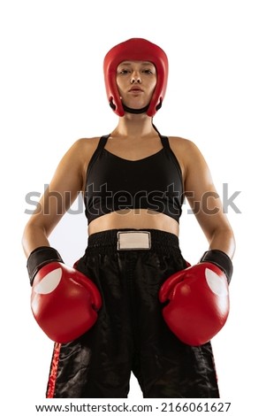 Portrait of professional female boxer in sports protective equipment posing isolated on white background. Sport, competition, hobby, results, success concept. Bottom view