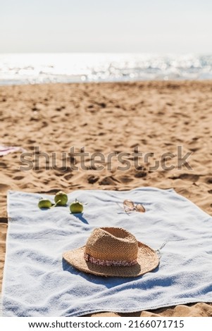 Summer beach accessories on sand background. Holiday travel, tropical concept. Straw hat, sunglasses, towel and fruits. Sun shadow and sunlight. Royalty-Free Stock Photo #2166071715