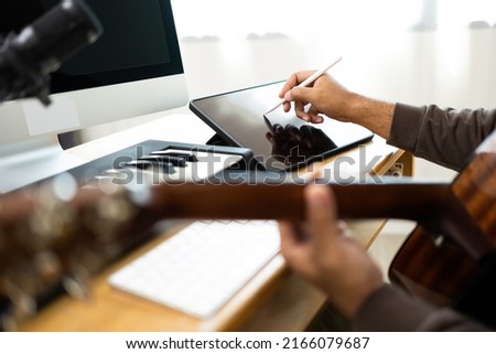 Close up hands song writer composing music note on tablet. Professional composer Recording Mixing and Mastering in home studio with keyboard and guitar. Digital music production Royalty-Free Stock Photo #2166079687
