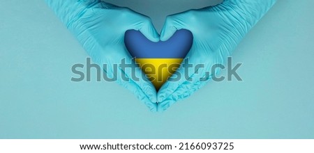 Doctors hands wearing blue surgical gloves making hear shape symbol with Ukraine flag