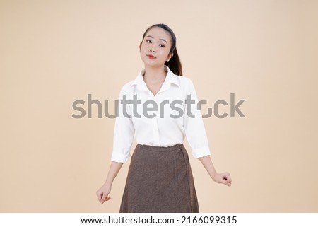 Portrait of Asian young beautiful and cheerful woman, point finger with hand gesture, isolated on background