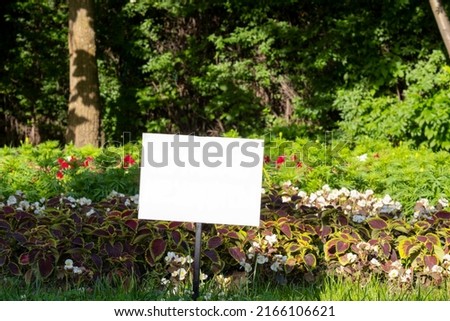 Sign on a flowerbed in the park with free space for text.
