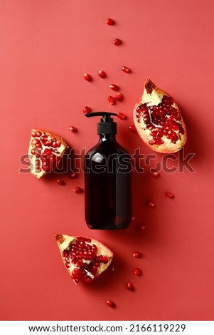 Pump brown bottle with pomegranate extract shampoo on red background. Flat lay, top view.