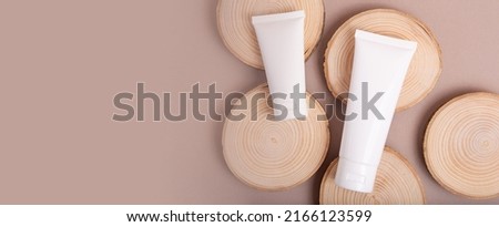 Top view of blank cosmetic tubes on wooden slices.Earth tones,eco friendly concept.Large banner with copy space.
