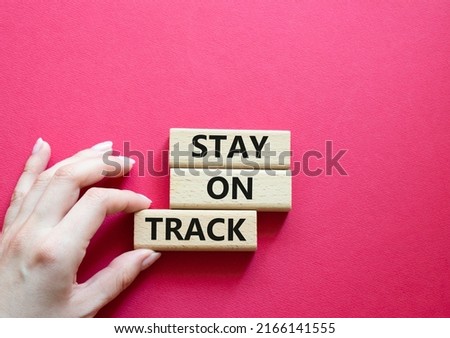 Stay on track symbol. Wooden blocks with words 'Stay on track'. Beautiful red background. Businessman hand. Business and 'Stay on track' concept. Copy space.