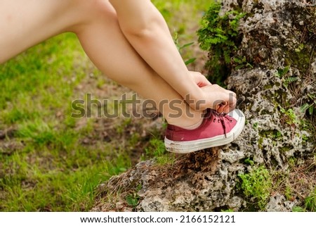 Young beautiful woman wearing sportive clothes on city park, outdoors tying running shoes leaning on a rock getting ready for run. Jogging girl exercise motivation health and fitness.