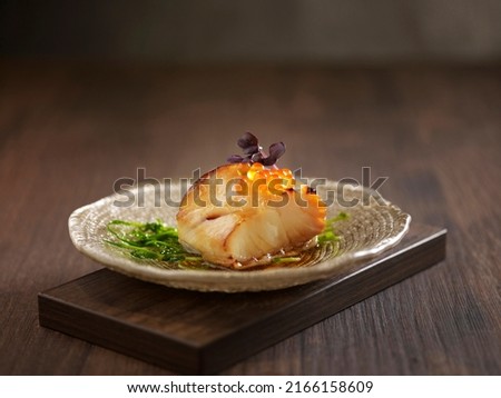 Baked Cod Fish with Honey Sauce served in a dish isolated on wooden board side view dark background