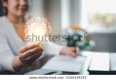 Woman hand hold light bulb with icons work on the desk, Creativity and innovation are keys success. Concept of new idea and innovation with icons and light bulbs, Save the money, Freedom of thought.
