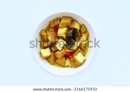 Indonesian traditional food named "sayur tahu kuah santan" i.e. tofu cooked with coconut milk and spices served on bowl isolated on white background