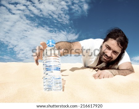 Thirsty man in the desert reaches for a bottle of water, toned image Royalty-Free Stock Photo #216617920