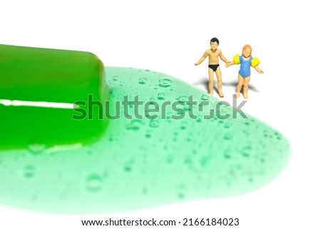 Miniature people toy figure photography. Creative summer vacation concept. Brother and sister looking on green watermelon melting ice cream. Isolated on white background. Image photo