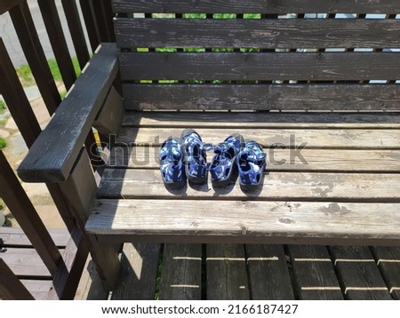 Some child's swim shoes left outside to dry on a bench.