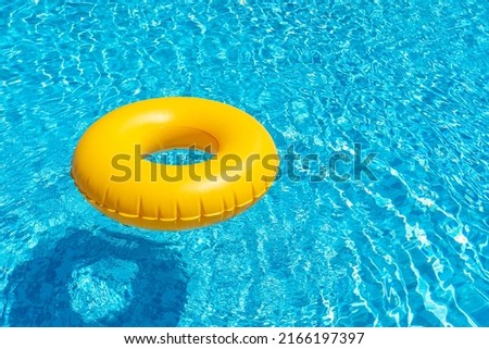 Yellow ring floating in blue swimming pool. Inflatable ring, rest concept Royalty-Free Stock Photo #2166197397