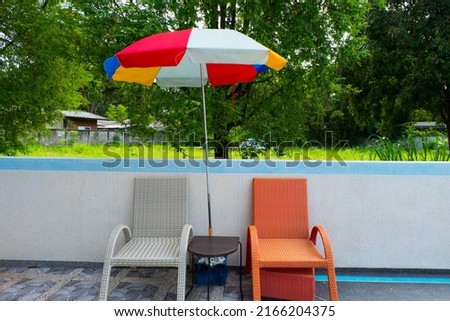 Empty Beach chairs with umbrella at Swimming pool.