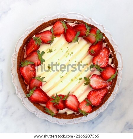 Delicious homemade tart with strawberries, cream cheese or whipped cream, jelly and pistachios. Berry cheesecake. Dessert. Pie. Cake.  Marble background. Top view, copy space, square picture