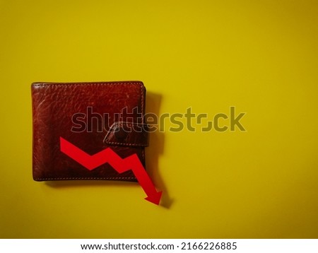 Brown wallet over the yellow surface. Concept of investment risk, rising cost of living and inflation.