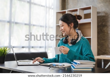Young attractive asian female employee with headphone listen to digital online course development program. Royalty-Free Stock Photo #2166230259
