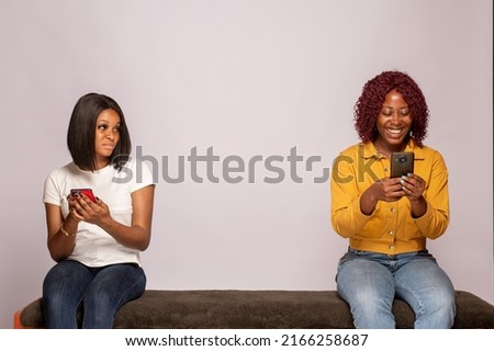 one girl happy another feels sad while checking their phones Royalty-Free Stock Photo #2166258687