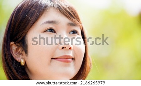 Smiling young businesswoman outdoors with trees in the background